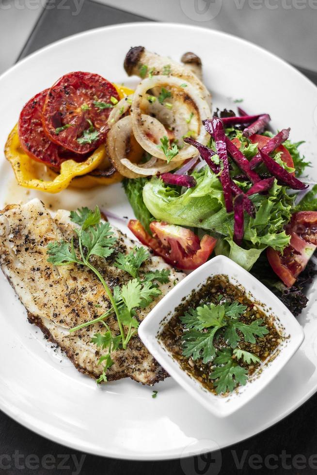 tilapia visfilet met gemengde salade gegrilde groenten en kruidenvinaigrettesaus foto