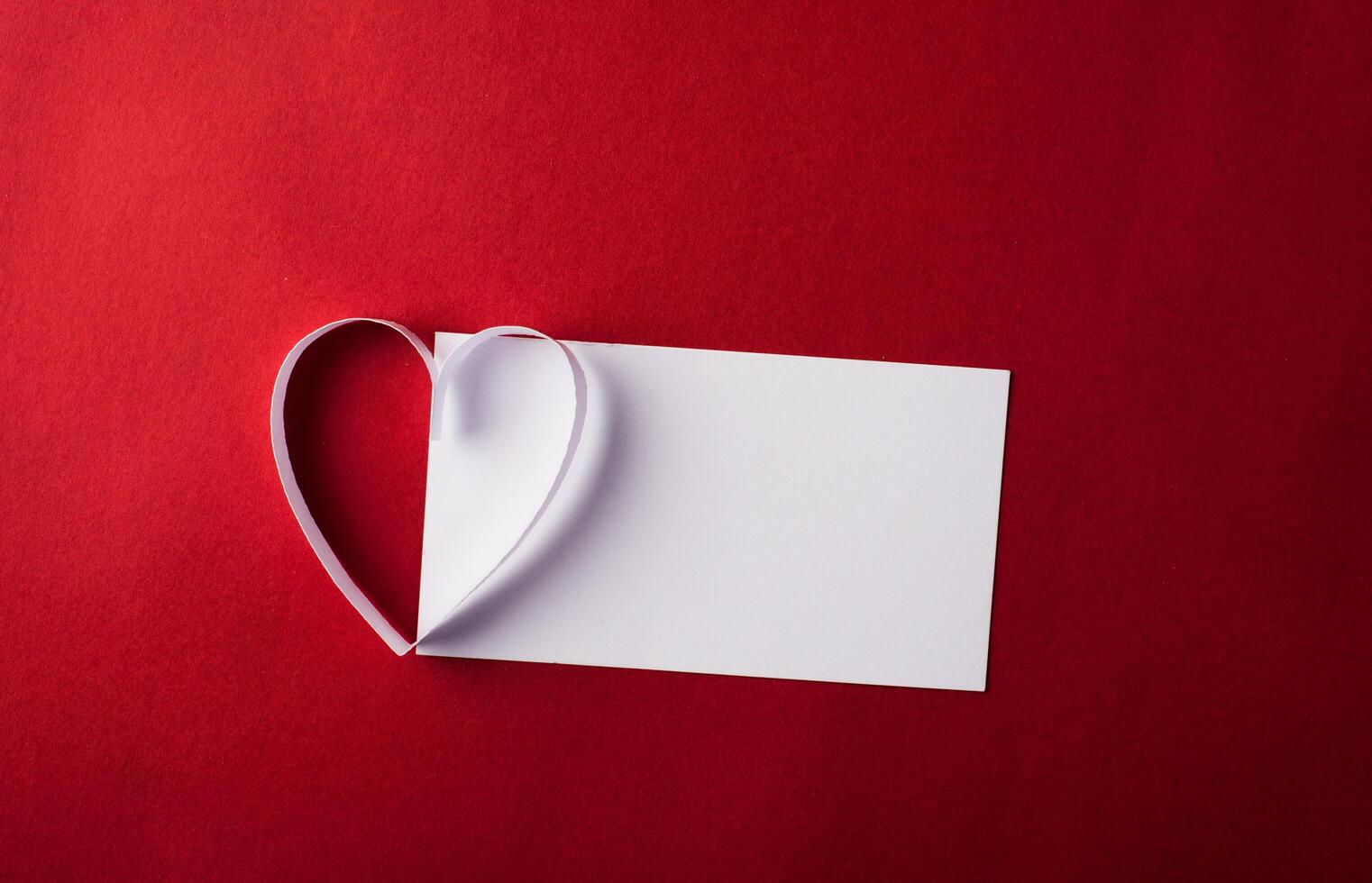 rood hartpapier en blanco met notitiekaart op rode achtergrond. foto