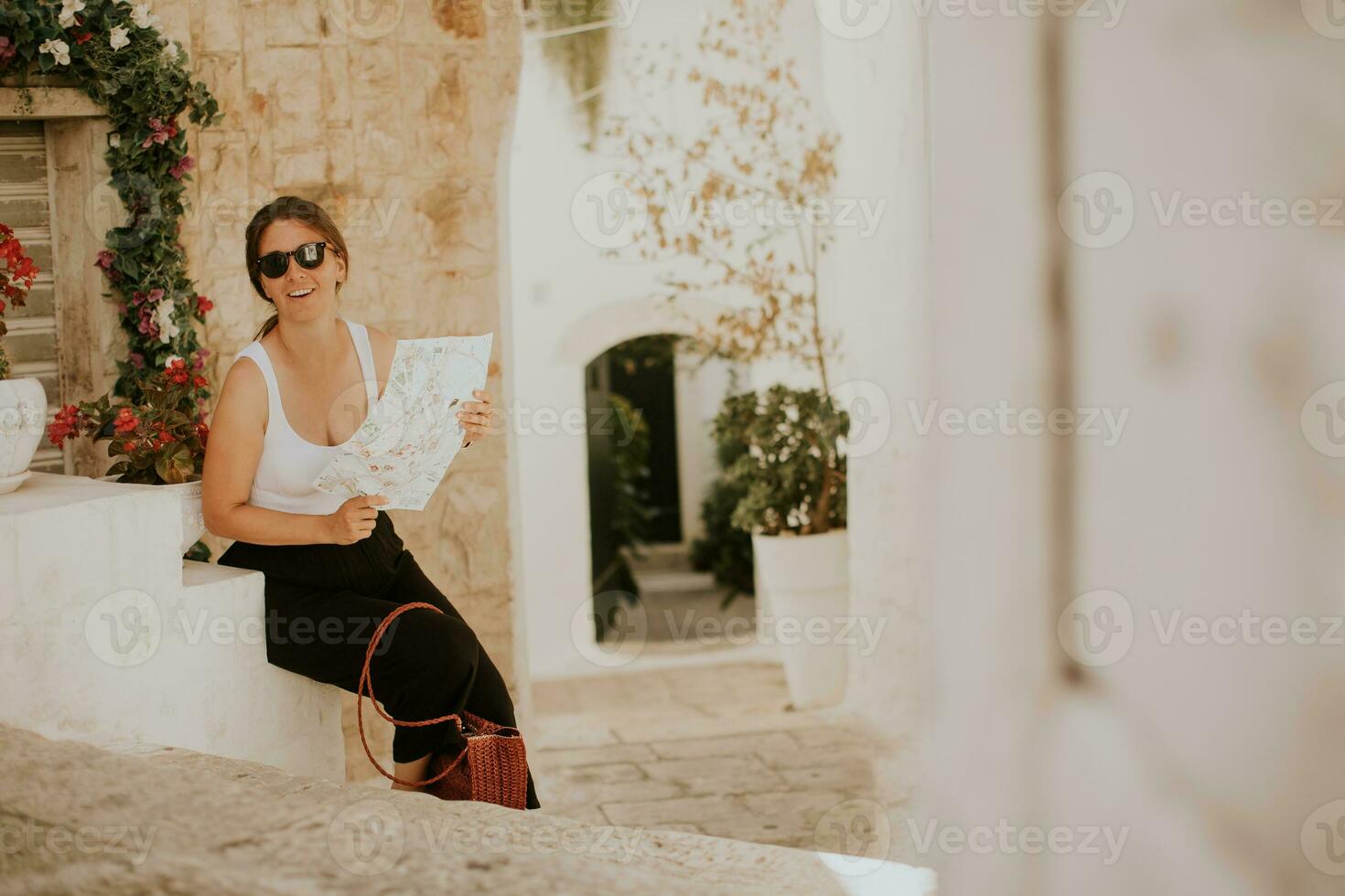 vrouw toerist met papier stad kaart Aan versmallen straten van ostuni, Italië foto