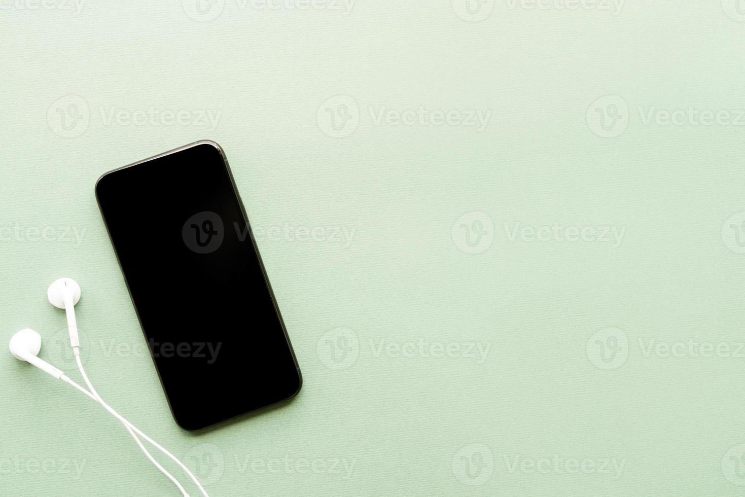 smartphone met leeg scherm koptelefoon op groene achtergrond foto