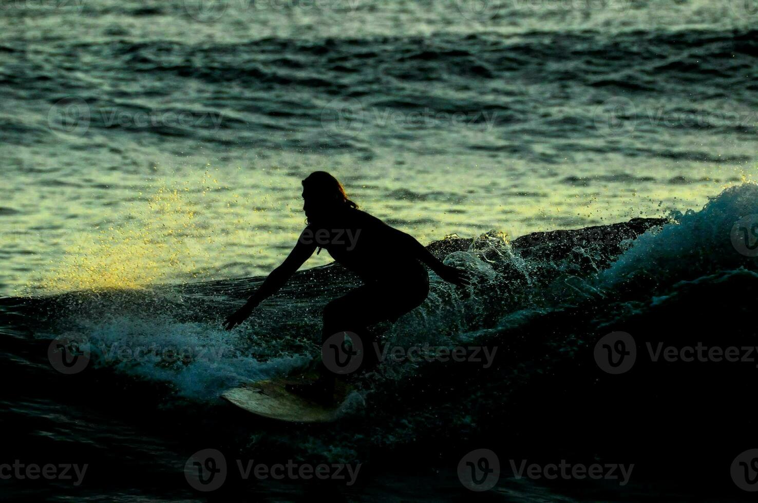 een surfer ritten een Golf Bij zonsondergang foto