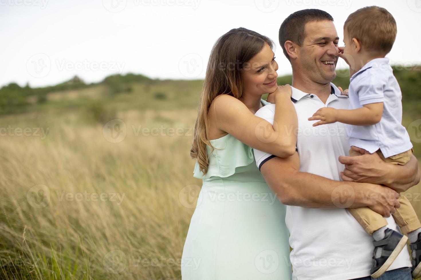 jong gezin met schattige kleine jongen die plezier heeft buiten in het veld foto