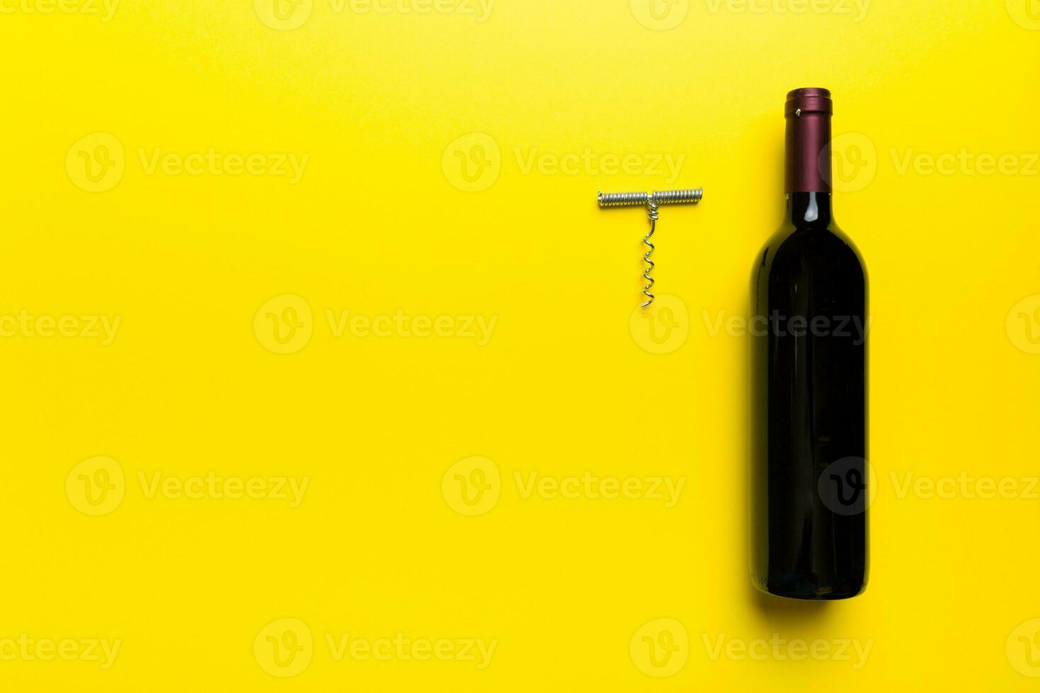 een fles van rood wijn met kurketrekker Aan gekleurde tafel. vlak leggen, top visie wth kopiëren ruimte foto