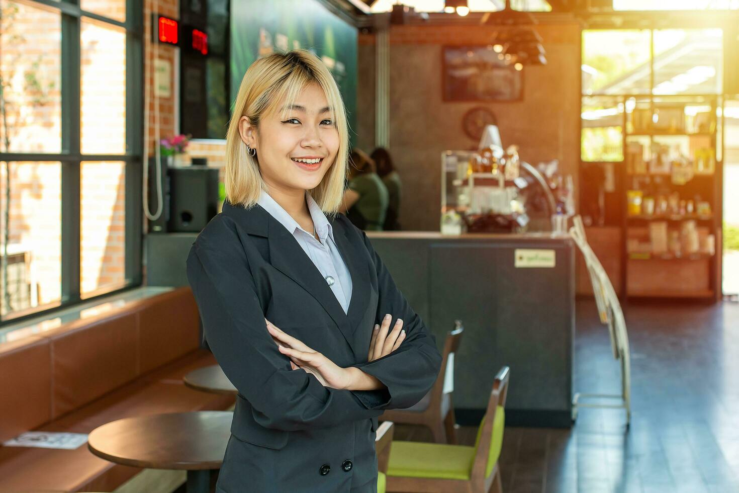 de mooi bedrijf meisje stond vol vertrouwen in voorkant van haar cafe, armen gekruiste en lachend, net zo ze welkom klanten naar ervaring de warm en uitnodigend atmosfeer binnen. foto