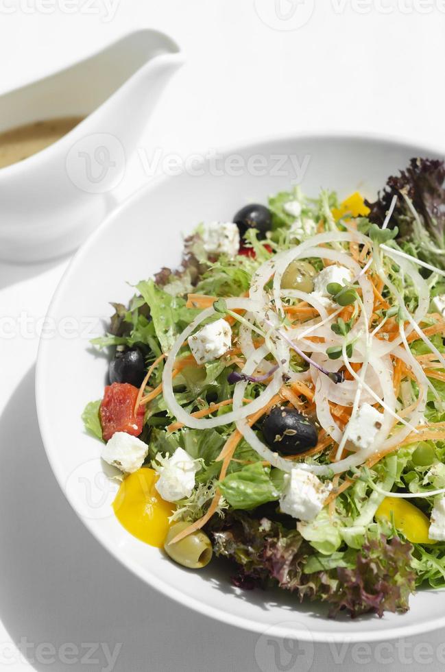 Griekse salade met fetakaas en olijven met citrusvinaigrette op houten tafel foto