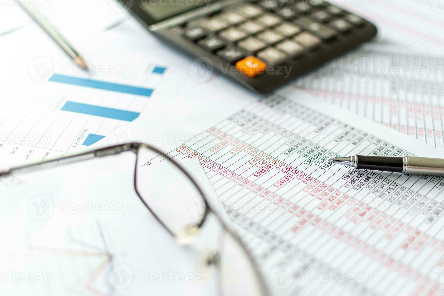 financiële boekhouding, thuiswerken, close-up man's hand met een pen die boekhoudnummers onderzoekt. getallen op papier en rekenmachine, veel getallen, grafiek, potlood, bril op papier, onscherpe achtergrond. foto