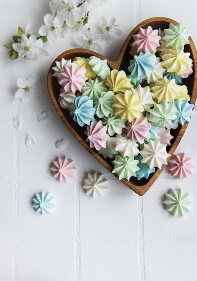 kleine kleurrijke meringues in de houten hartvormige kom foto