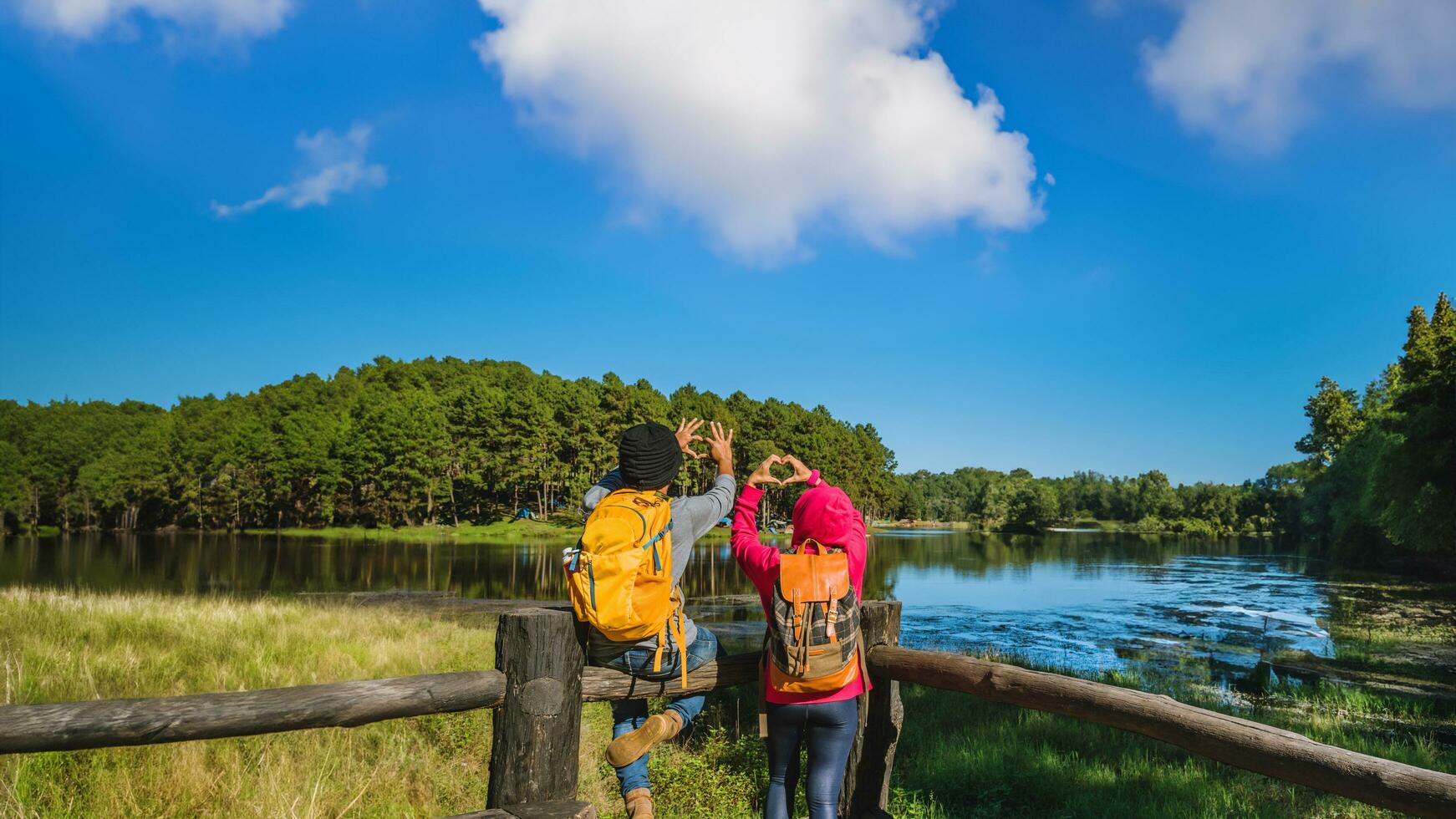 paren reizigers met rugzak gelukkig naar kom tot rust Aan berg, met meren, mooi vijvers pijnboom bossen. paren verhogen hun handen naar maken een hart vorm geven aan. gelukkig en zoet liefde. foto