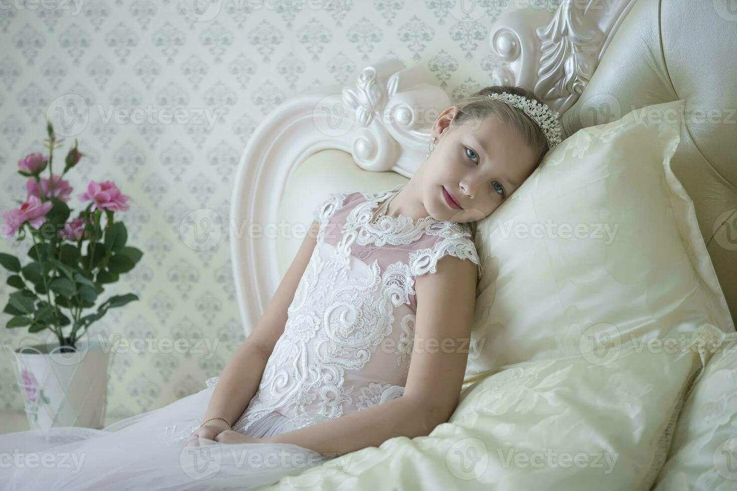 schattig inschrijving meisje tiener leugens Aan de bed. prinses in een wit jurk met een kroon. foto