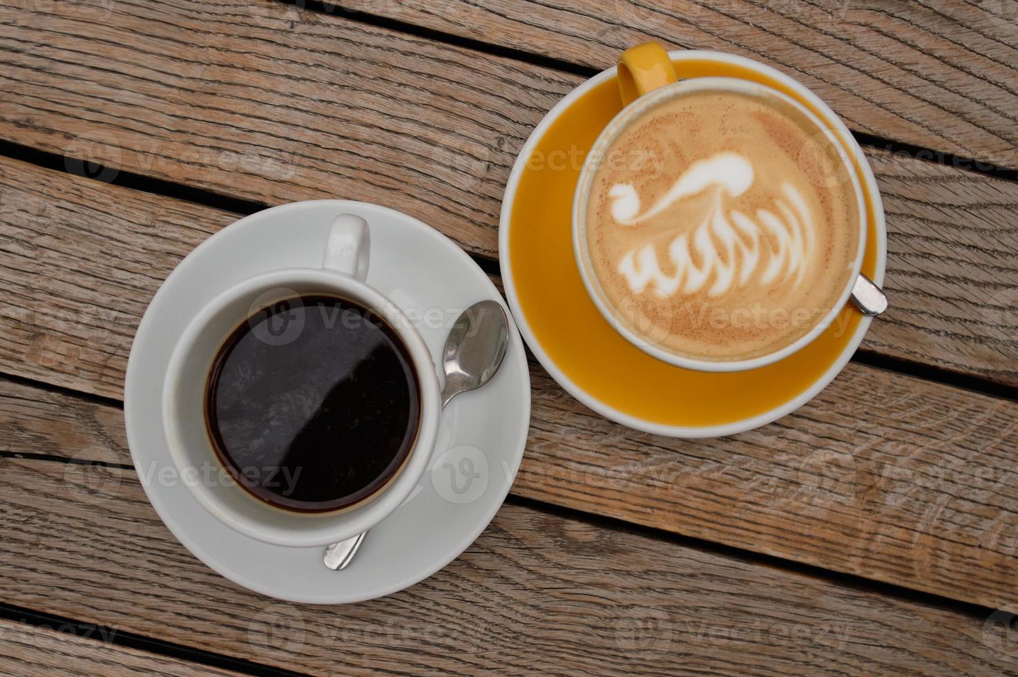 cappuccino met latte art en zwarte koffie op een houten tafel foto
