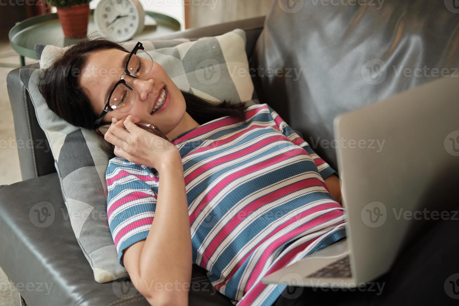 aziatische vrouw die thuis werkt, ligt en een mobiele telefoon gebruikt. foto