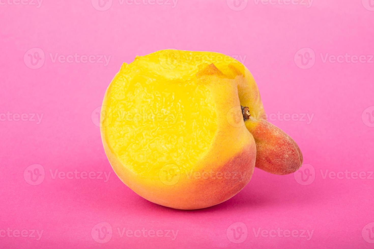 perzik sexy vrucht van een ongebruikelijke vorm met kopie ruimte op roze achtergrond. foto