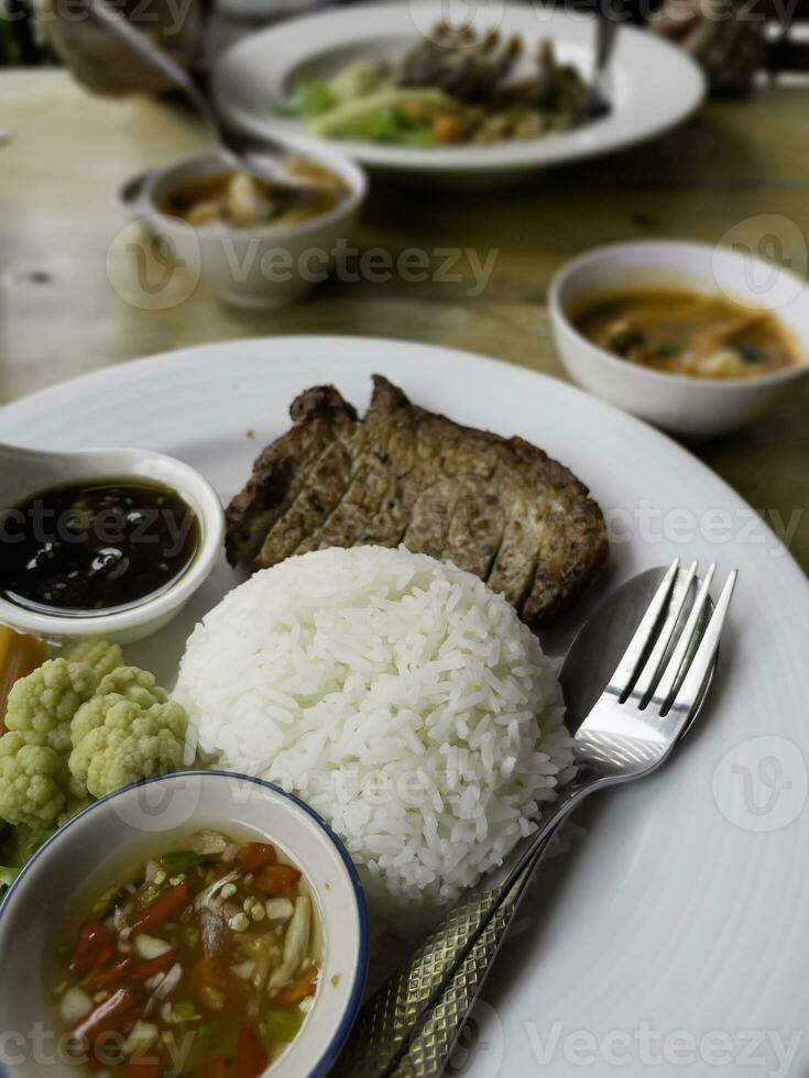 Thais rijst- lokaal varkensvlees karbonade steak met pittig saus en groenten foto