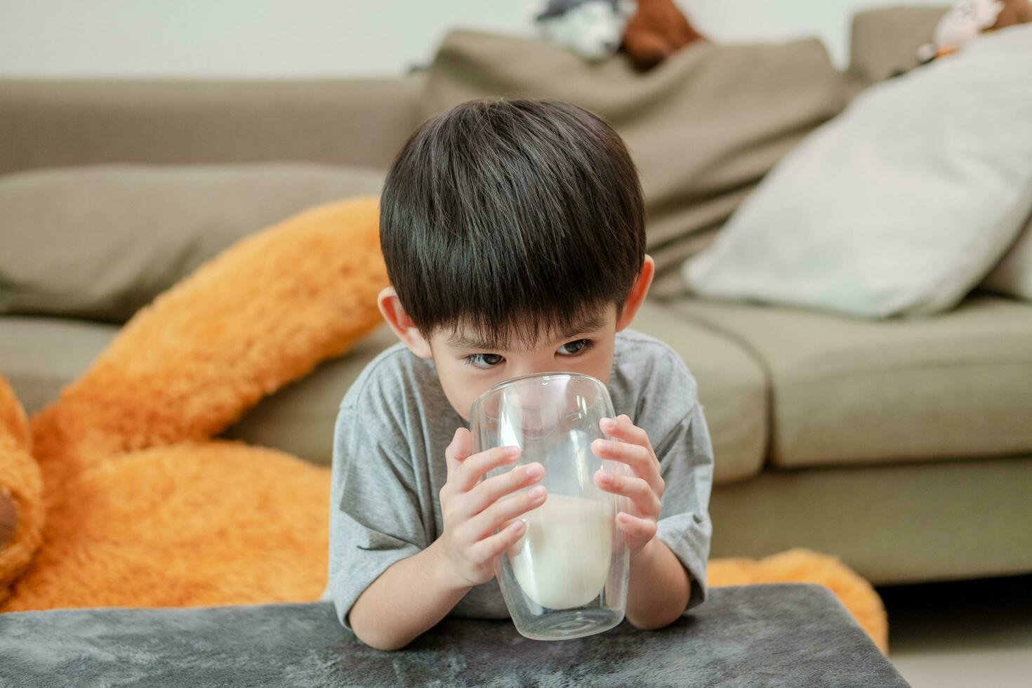 Aziatisch jongen is drinken een glas van melk foto