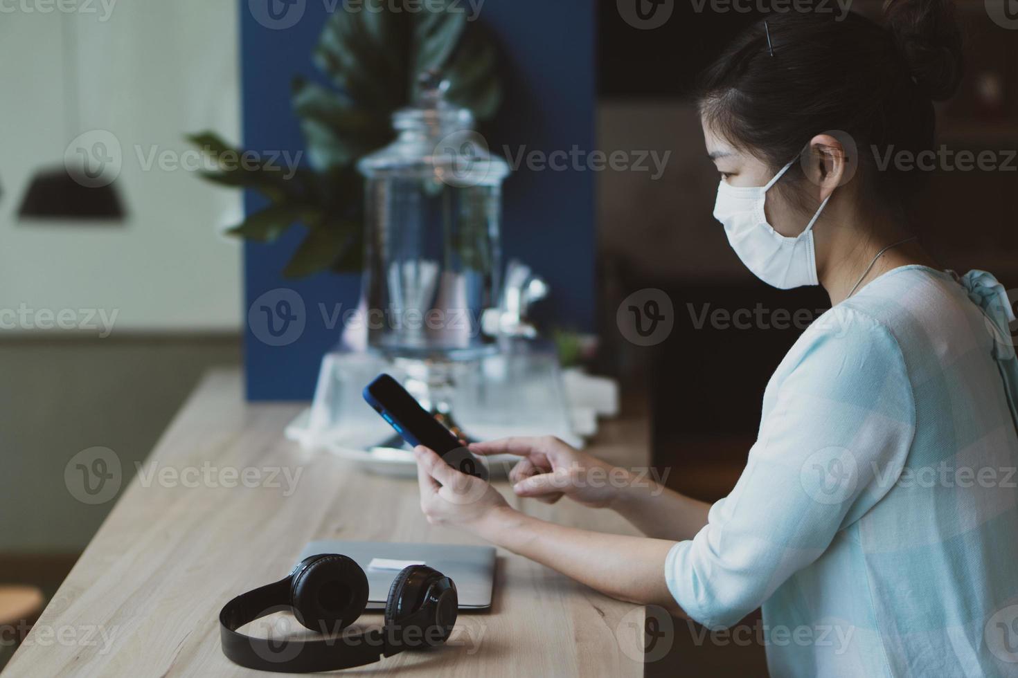 jonge aziatische vrouw die masker in café draagt foto