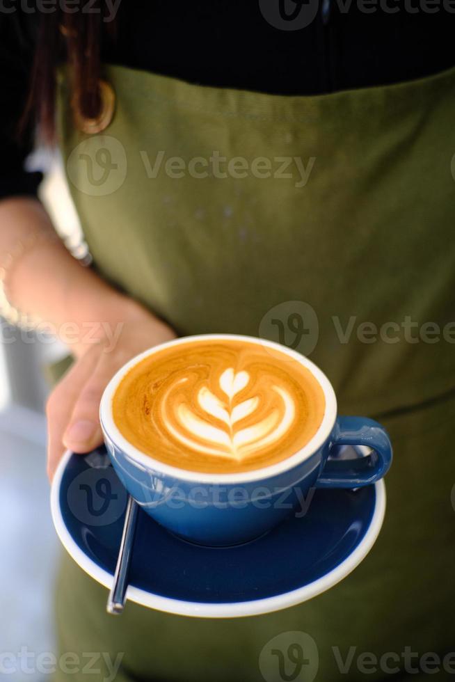 barita handen met een latte art warme koffiedrank foto