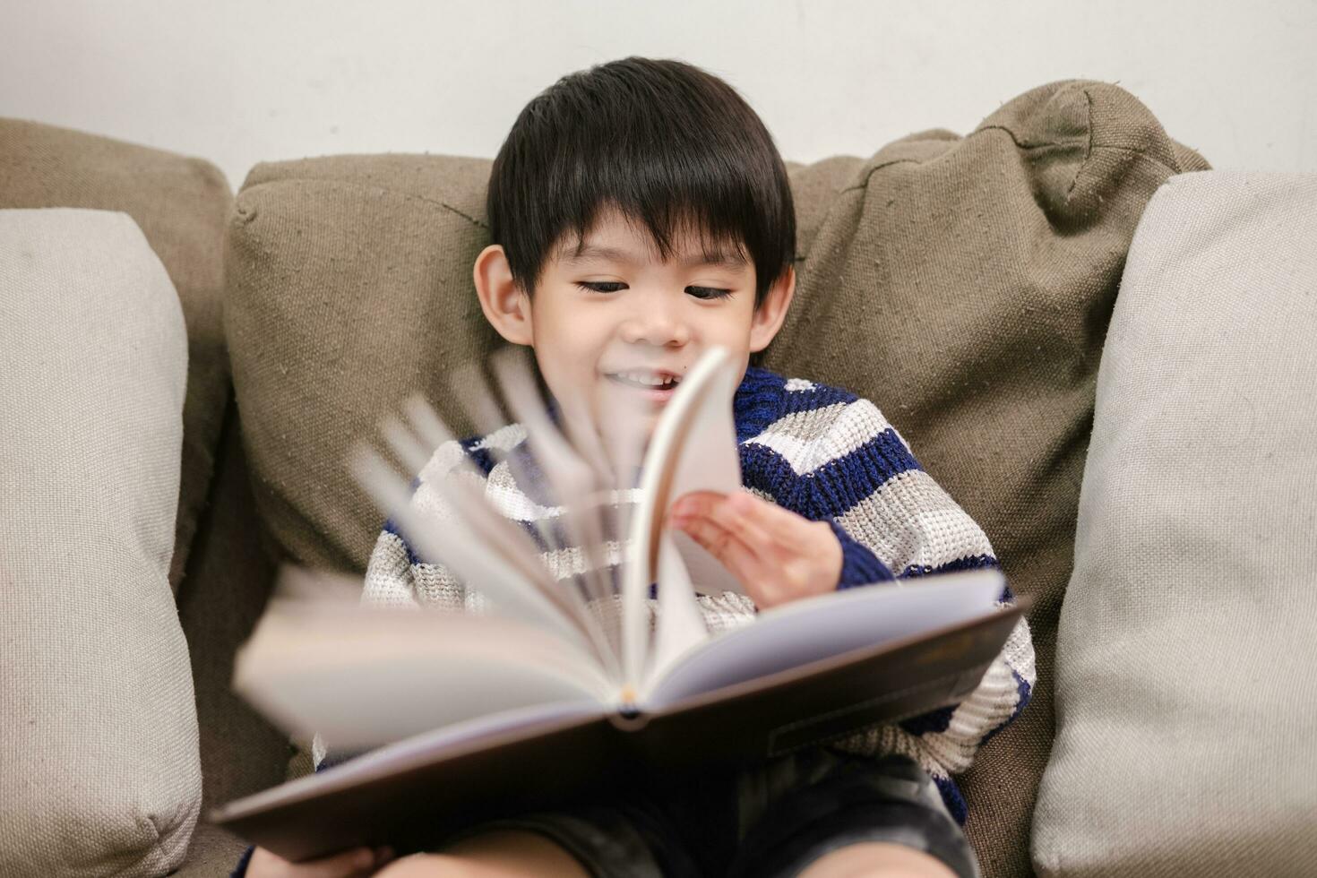 Aziatisch jongen lezing een boek Aan de sofa aan het leren buiten de klas foto