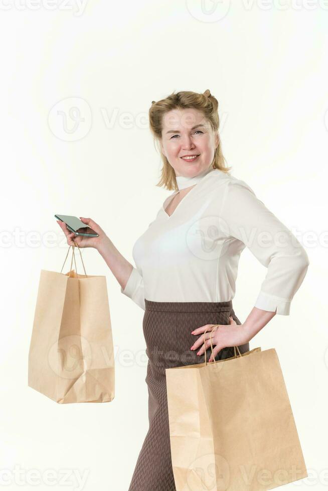 volwassen vrouw Holding beschikbaar papier pakket Tassen met aankopen na winkelen, gebruik makend van mobiel telefoon foto