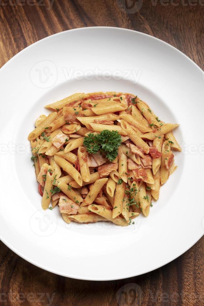 penne amatriciana tomaat en ham saus pasta op houten tafel achtergrond foto