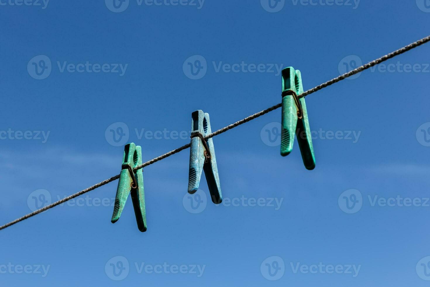 drie wasknijpers hangende Aan een Kledinglijn met blauw lucht foto