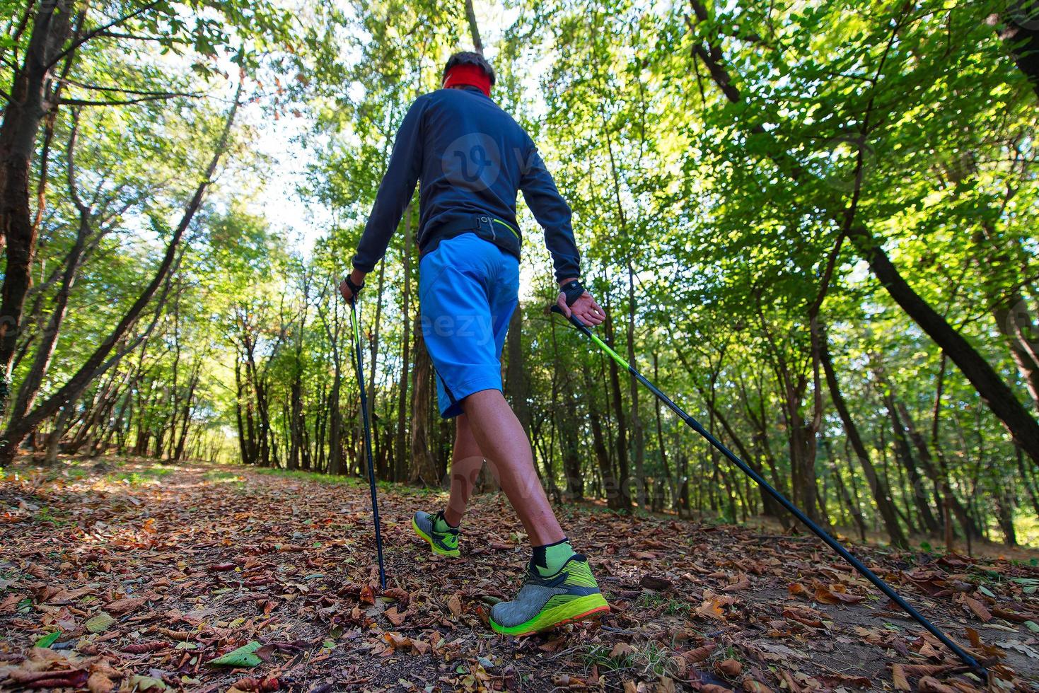 een man die nordic walking beoefent in het herfstbos tussen de bladeren foto