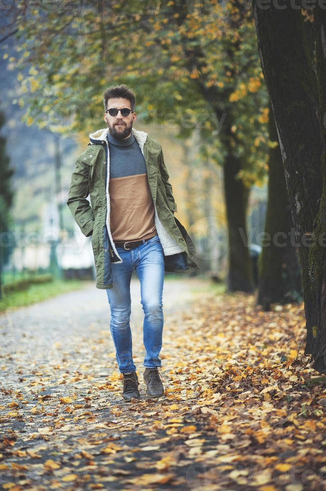 casual hippie-achtige man die tussen herfstbladeren loopt foto