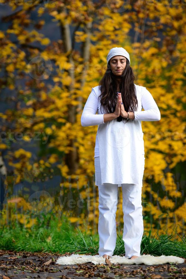 vrouw in het wit beoefent yoga in de natuur in de herfst foto