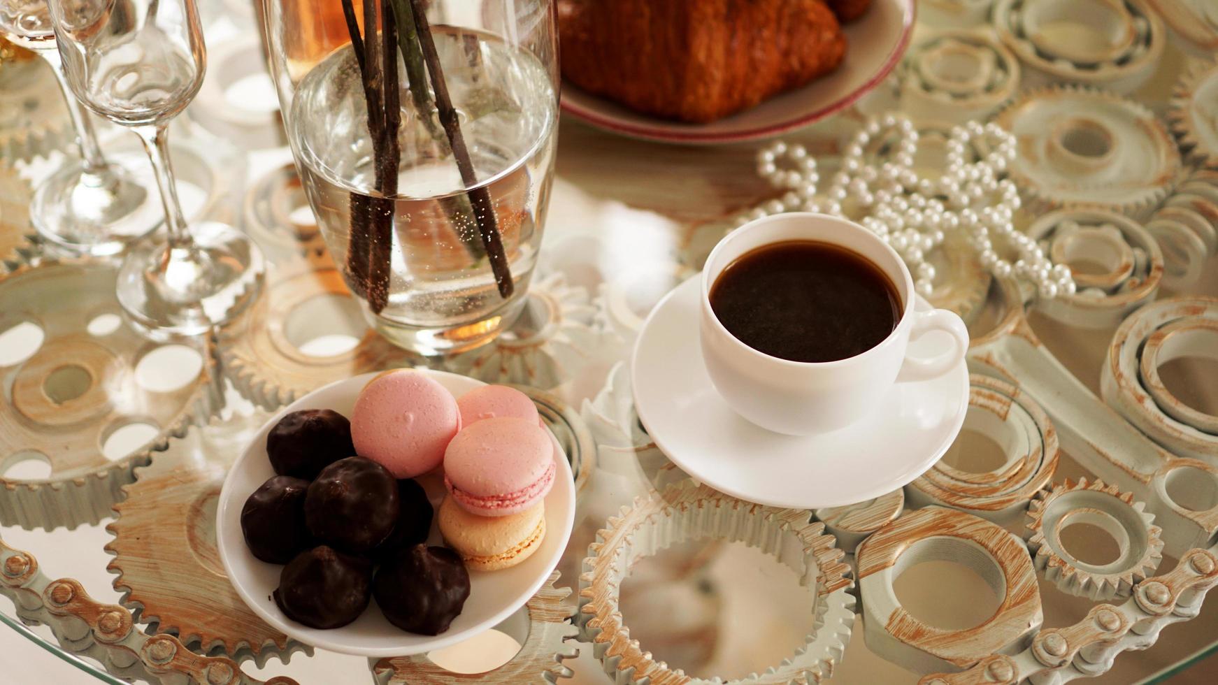 glazen tafel met een kopje koffie, zoete bitterkoekjes. foto