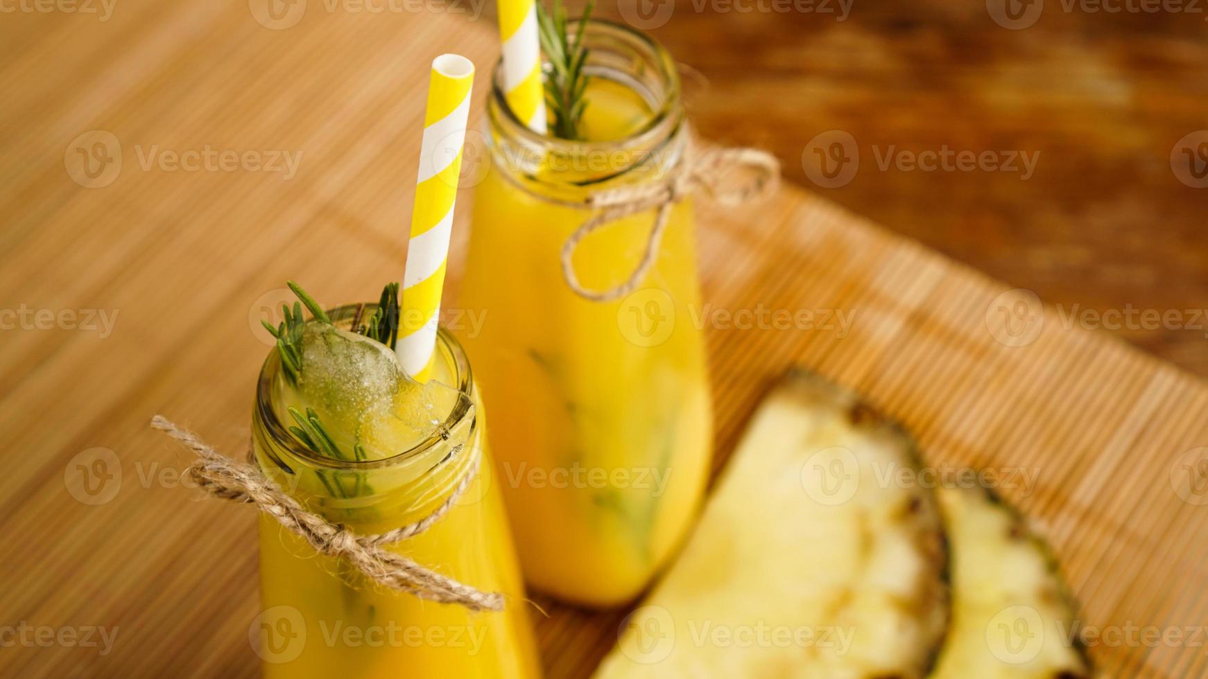 vers gemaakt ananassap met ijs in een kleine glazen fles foto