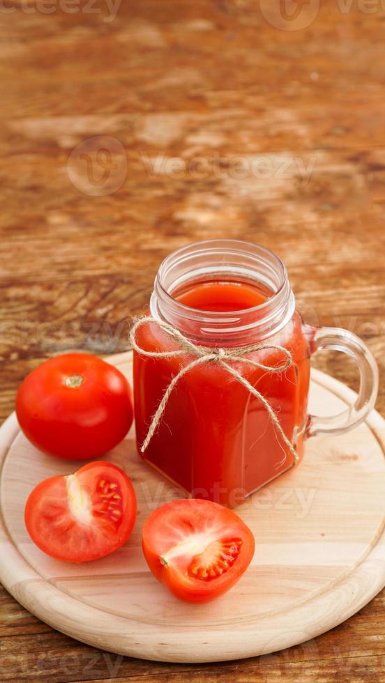 glas tomatensap op houten tafel. vers tomatensap foto