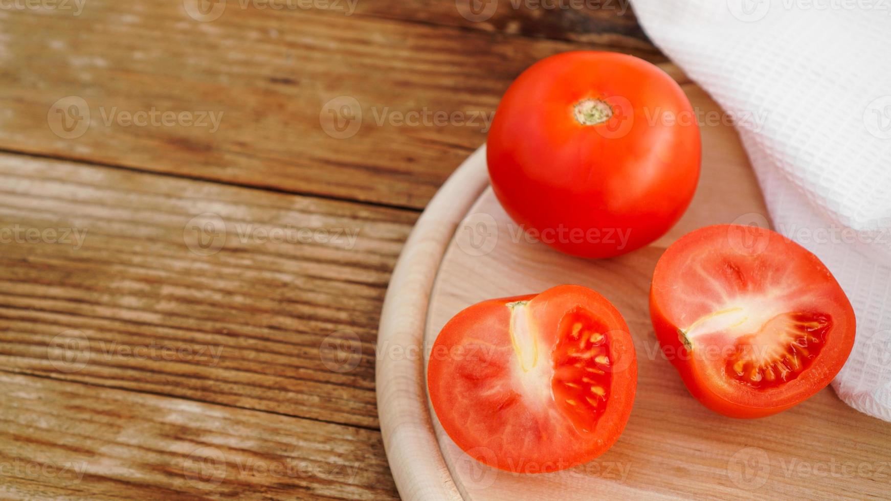 hele en gesneden tomaat op een houten bord om in plakjes te snijden foto