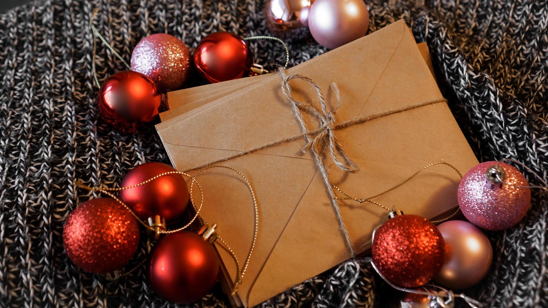 stapel brieven van kraftpapier met rode en roze kerstballen foto