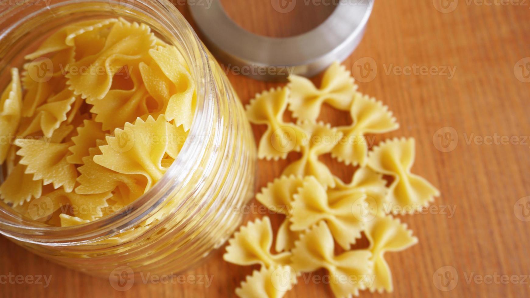 pasta in de vorm van strikken verspreid uit een glazen pot foto