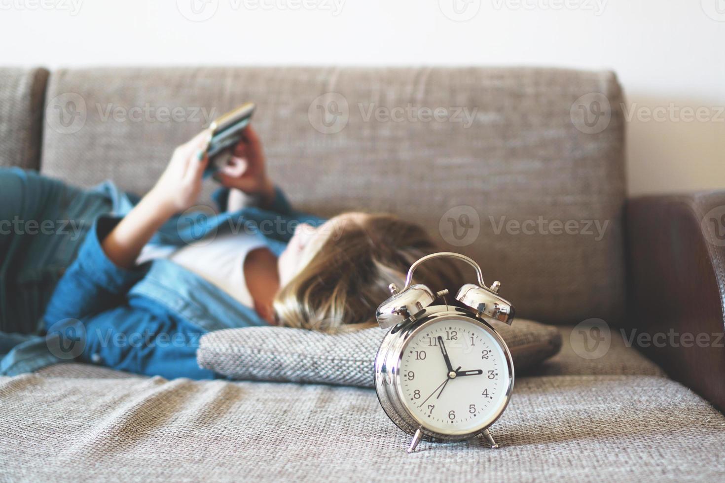 jonge vrouw die telefoon in bed gebruikt, naar het scherm kijkt foto