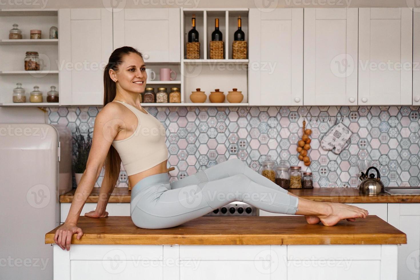 atletische vrouw in sportkleding poseren op tafel foto