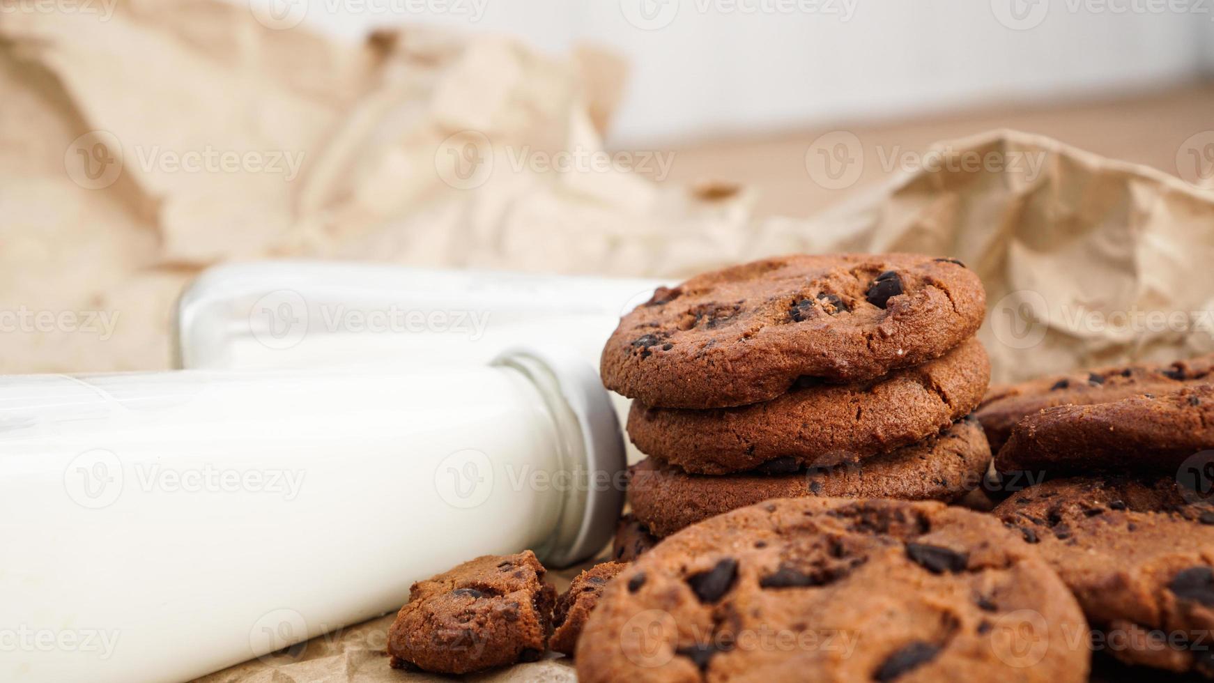 koekjes met chocoladedruppels op kraftpapier en flessen melk foto