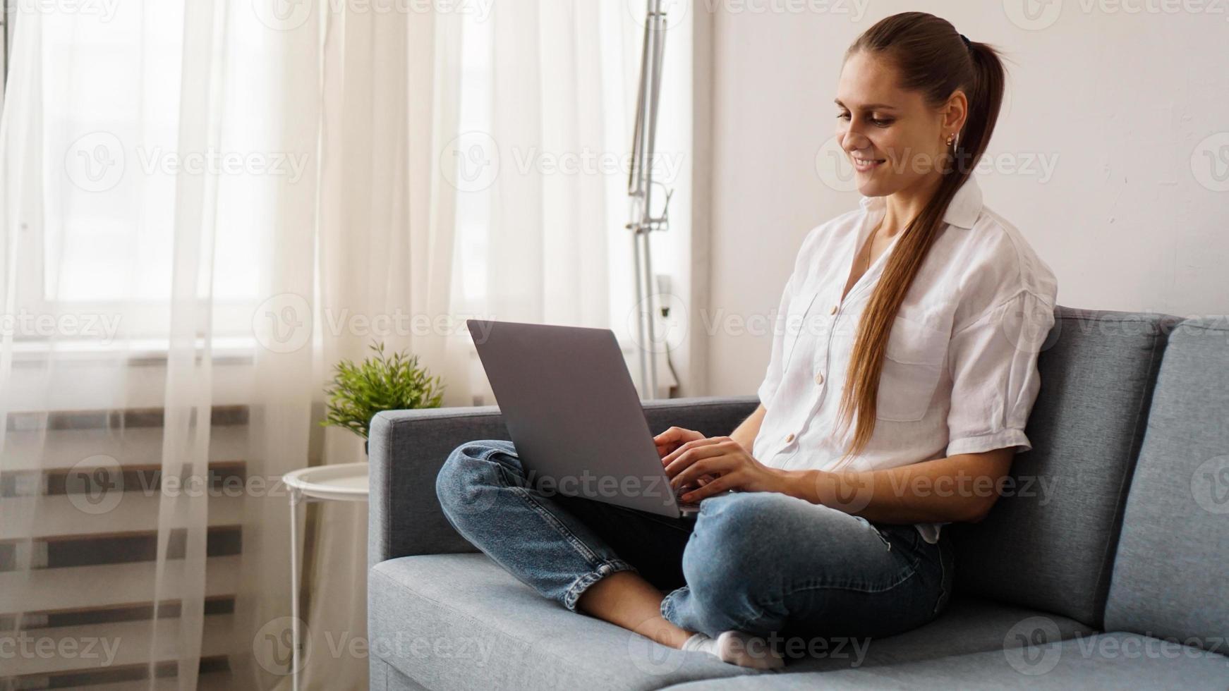 lachende gelukkige vrouw zittend op de bank en met behulp van laptop foto