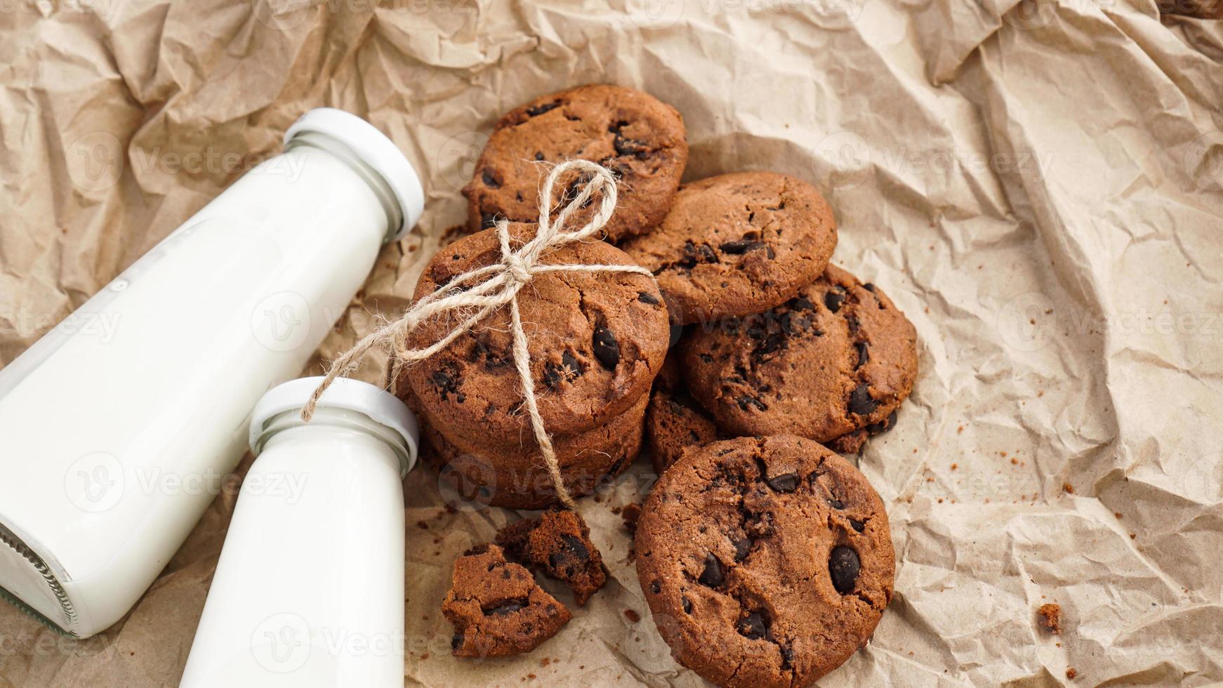 koekjes met chocoladedruppels op kraftpapier en flessen melk foto