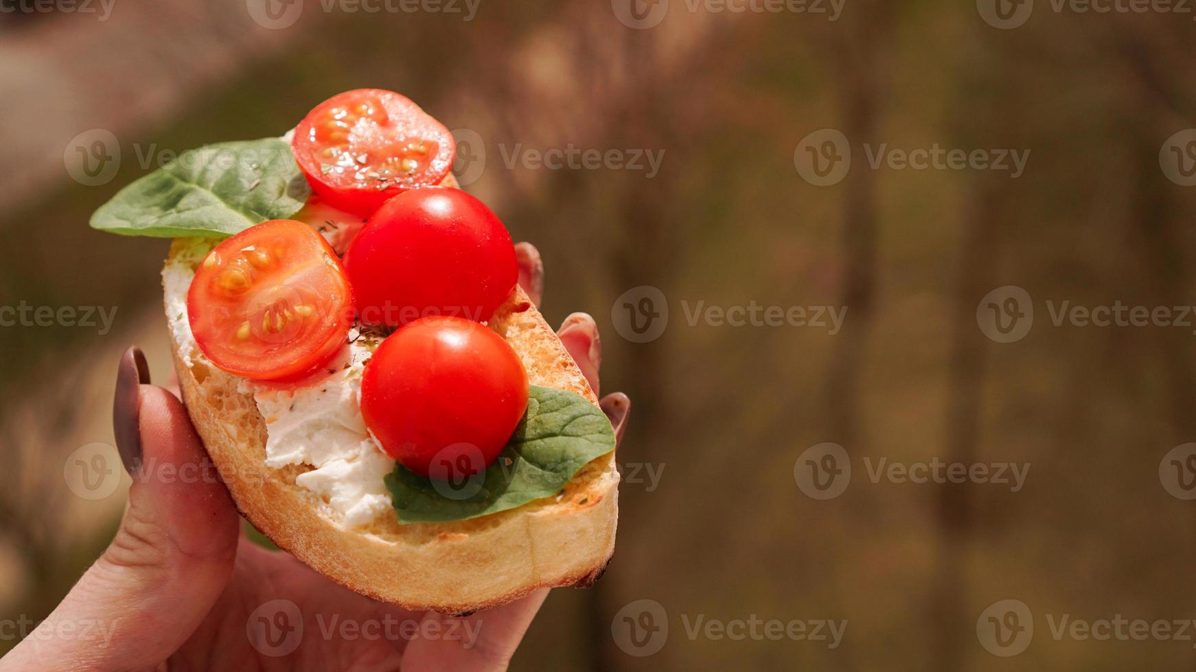 vrouwenhand met cherrytomaat bruschetta. Italiaans wijnvoorgerecht foto