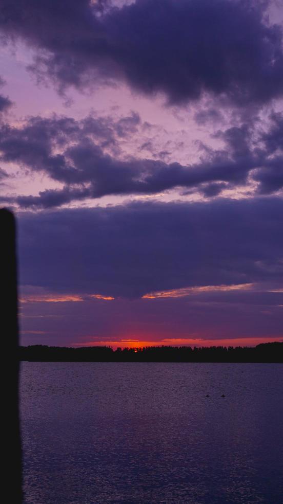violet paarse zonsondergang, zwarte zee-oppervlak onder de hemel foto