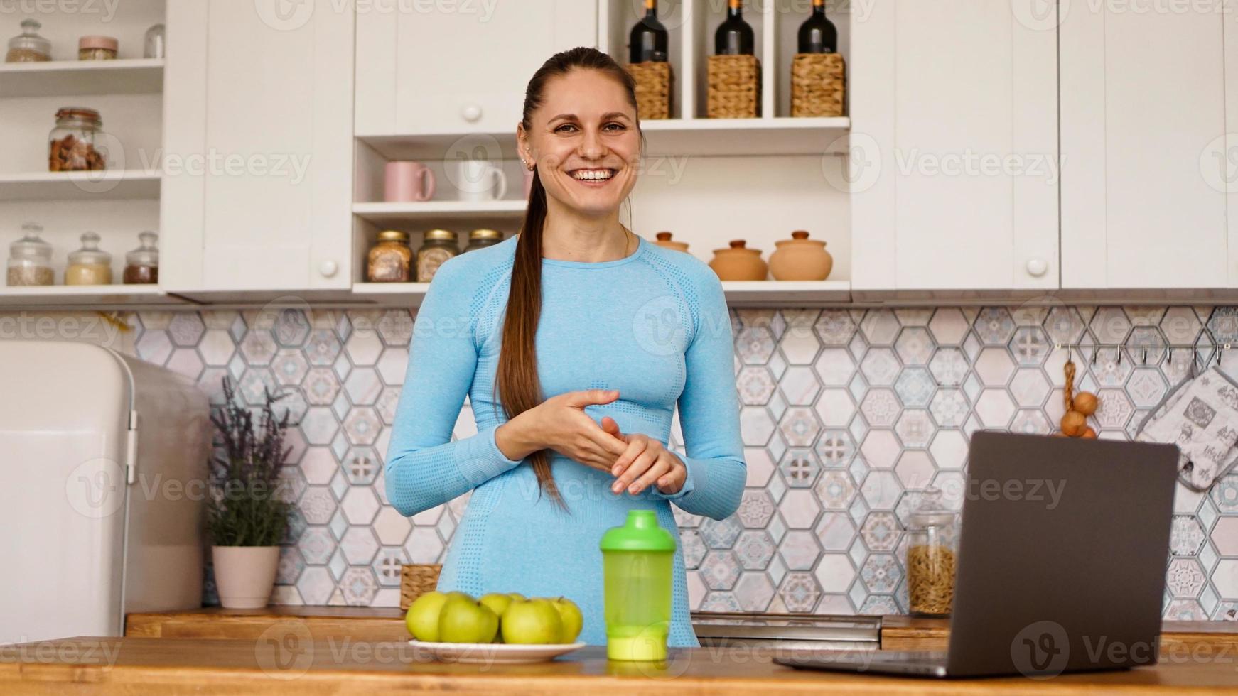 lachende vrouw met behulp van computer in moderne keuken foto