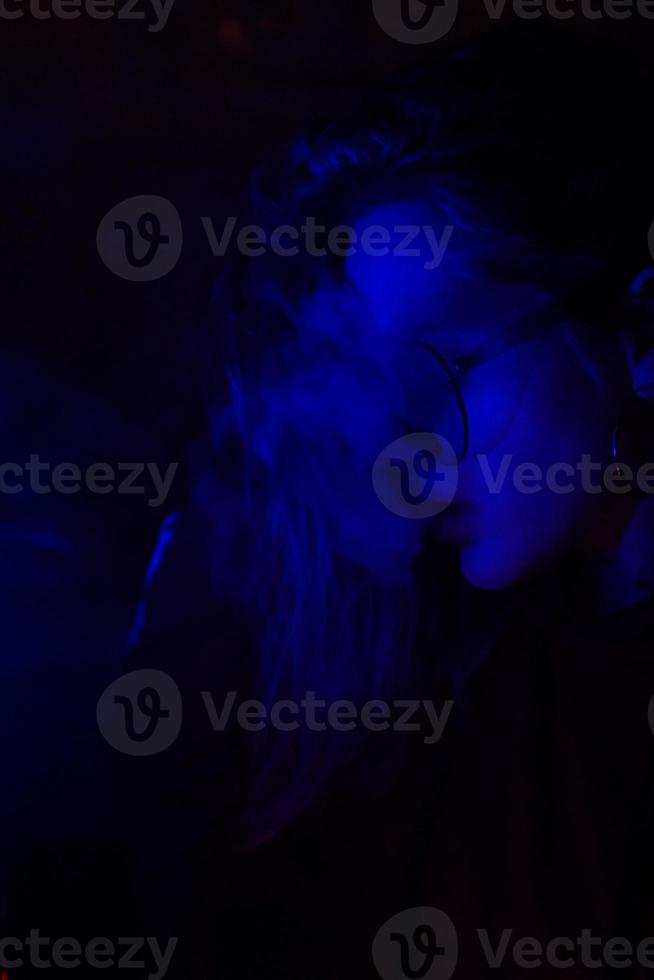 close-up portret van vaping meisje in neon blauw licht foto