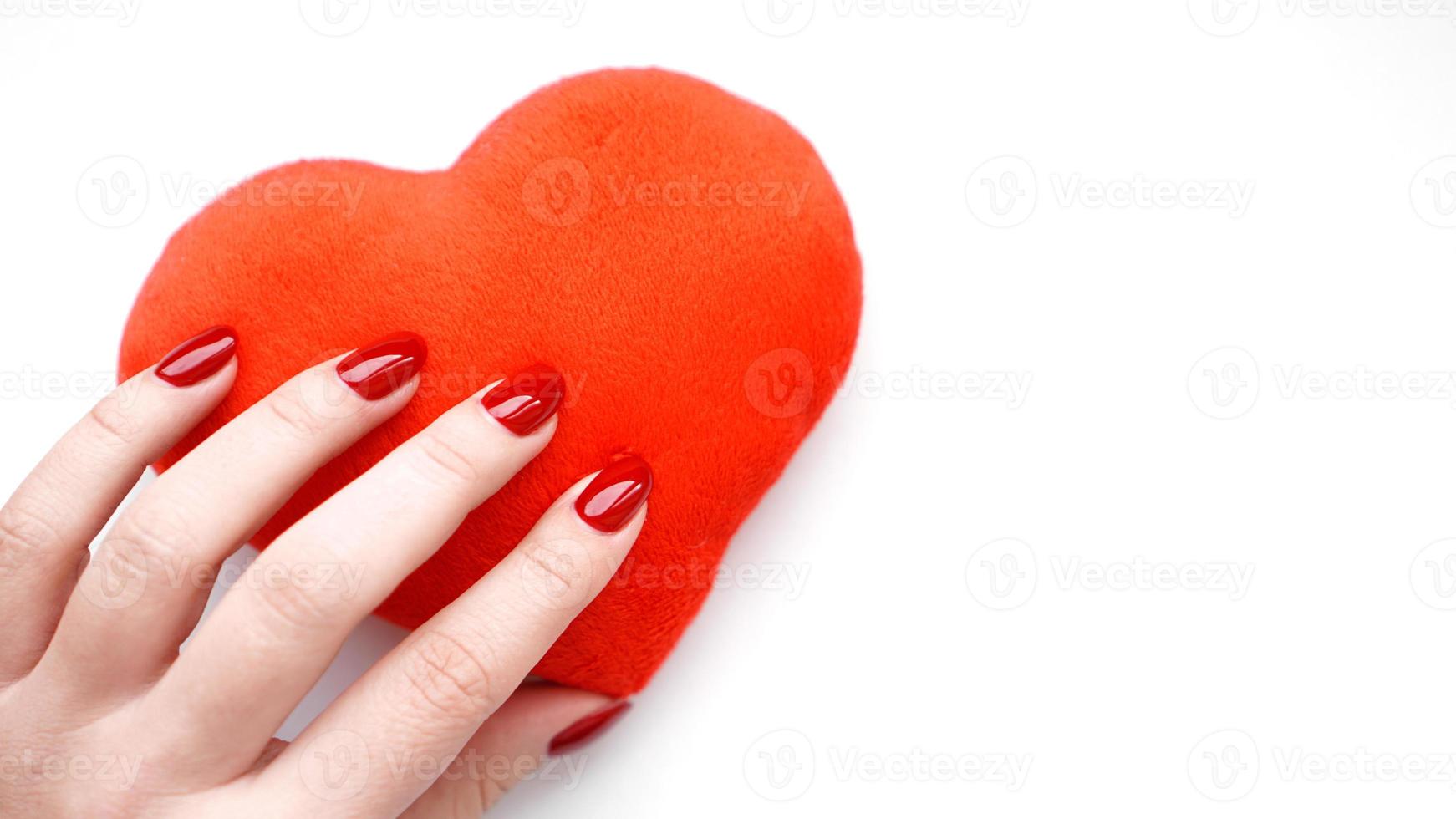 vrouwelijke hand met rood hart op wit wordt geïsoleerd foto