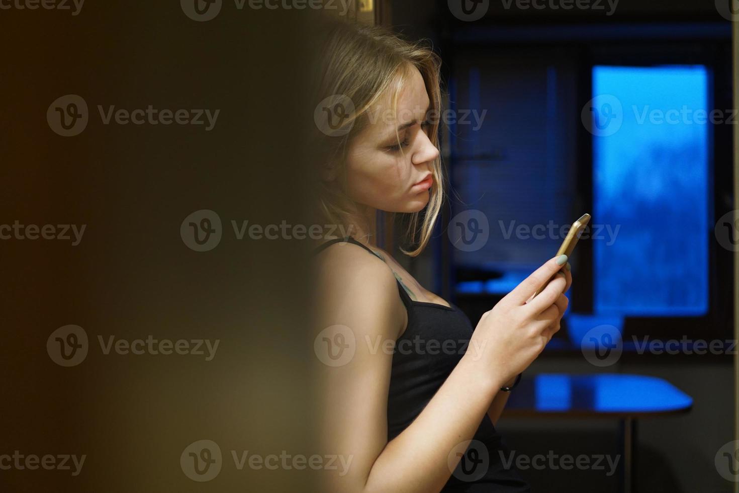 Europese jonge vrouw houdt moderne telefoon vast, gekleed in vrijetijdskleding foto