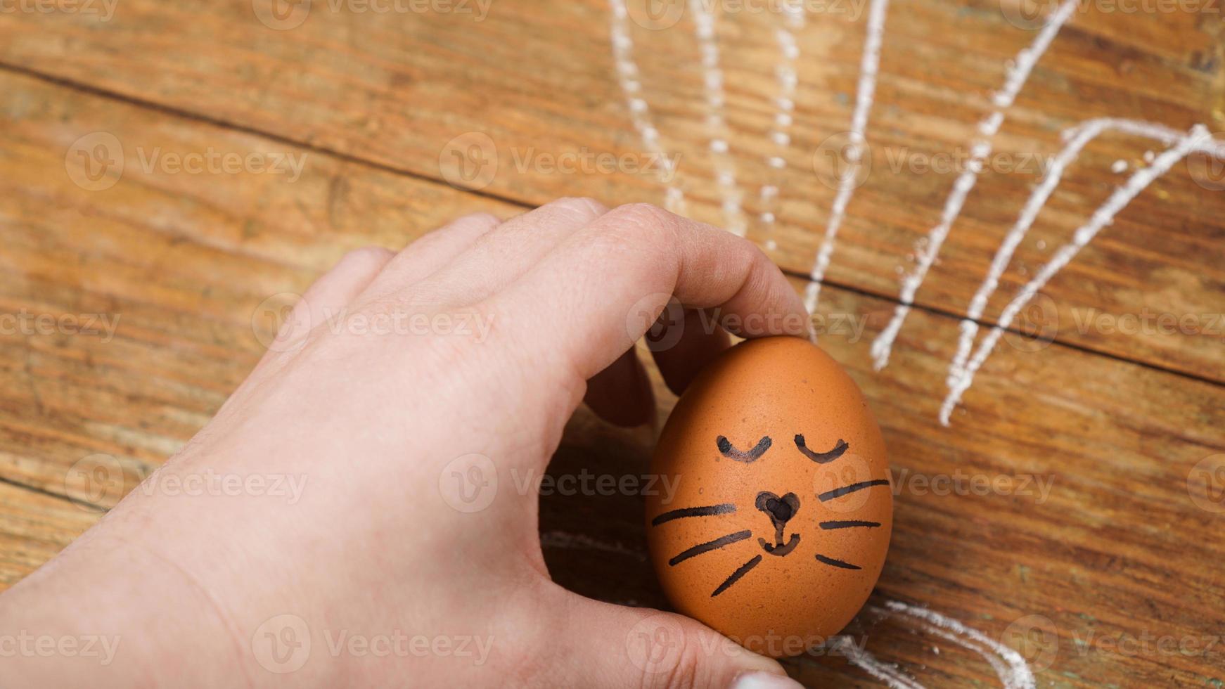 een vrouwelijke hand houdt een ei vast met een schattig gezicht. foto