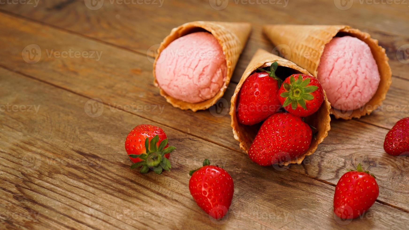 Aardbeienroomijs in een wafelkegel. rode bessen en ijsballen foto