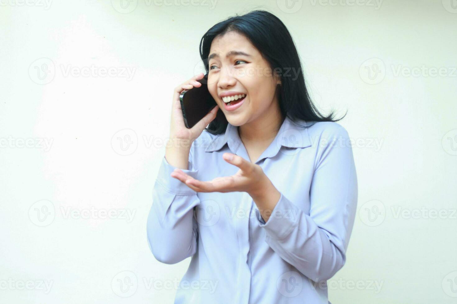 portret van verheugt Aziatisch bedrijf vrouw lachend opgewonden terwijl sprekend Aan mobiele telefoon met hijs- Open palm op zoek weg slijtage formeel overhemd staand geïsoleerd over- wit achtergrond foto