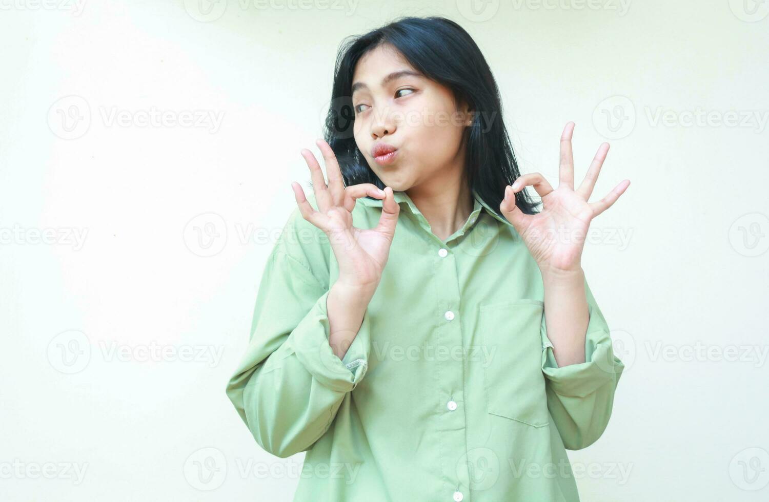 vervolg blij Aziatisch vrouw vervelend groen over- grootte overhemd tonen OK tekens met twee handen en op zoek terzijde naar leeg ruimte geven uitstekend gebaar en compliment staand geïsoleerd wit achtergrond foto