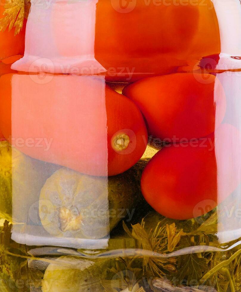 gezouten komkommers en tomaten in een glas pot foto