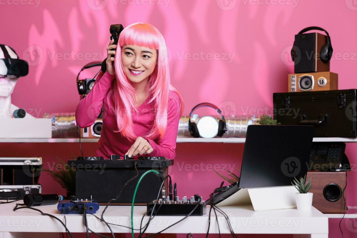 artiest met roze haar- menging techno lied Bij professioneel draaitafels luisteren muziek- met koptelefoon terwijl aan het doen prestatie in club gedurende nacht. vrouw opname album gebruik makend van audio uitrusting foto